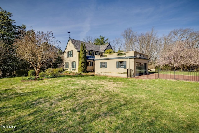 rear view of house with fence, stucco siding, an attached garage, and a lawn