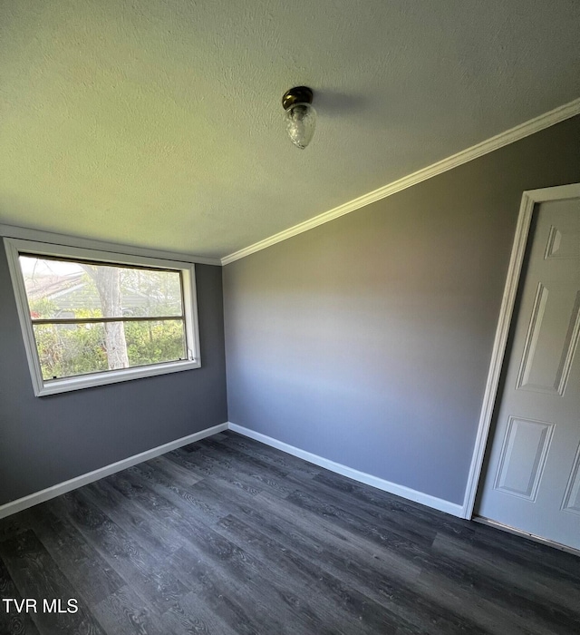 empty room featuring dark wood-type flooring, a textured ceiling, baseboards, and ornamental molding