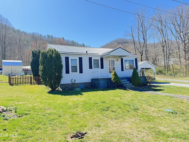 view of front of property featuring metal roof, a front yard, and fence