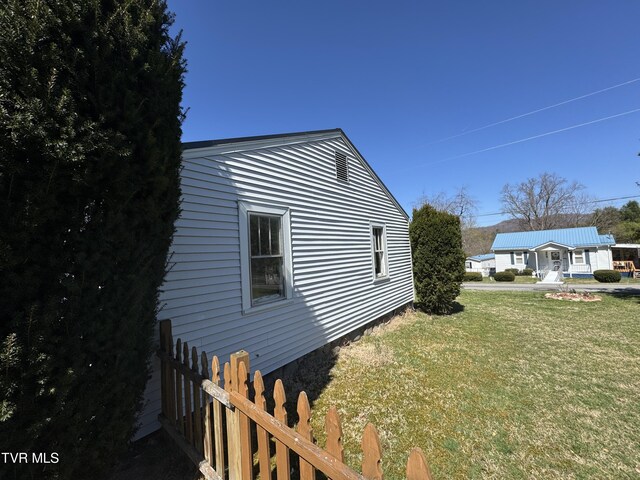 view of side of property with fence and a lawn