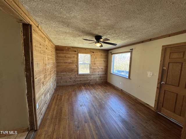 spare room with hardwood / wood-style floors, a textured ceiling, ceiling fan, and wood walls
