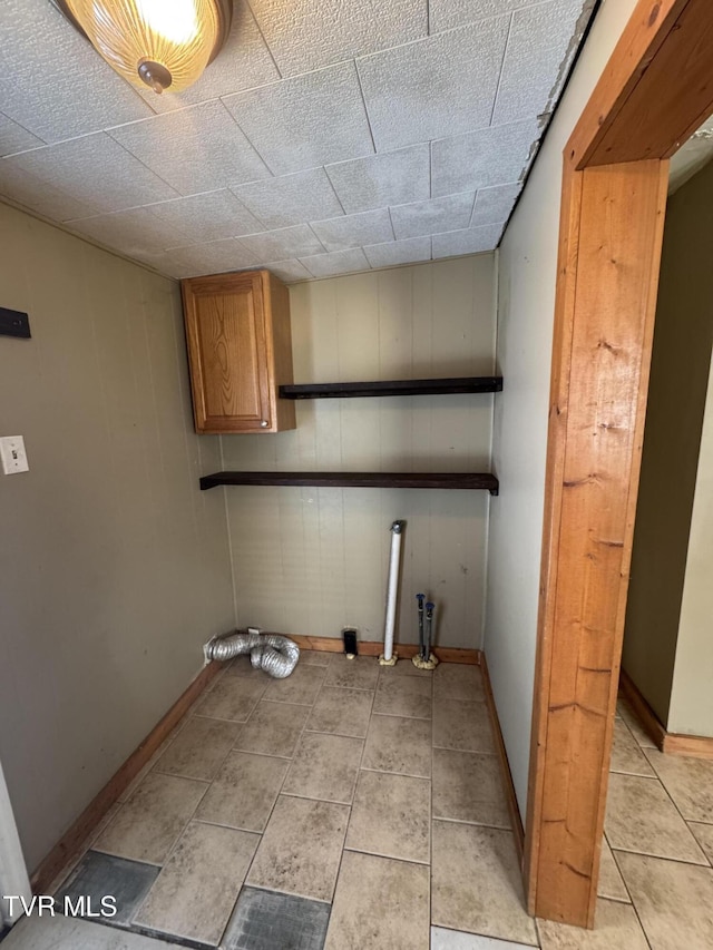 laundry room featuring baseboards, cabinet space, and light tile patterned floors