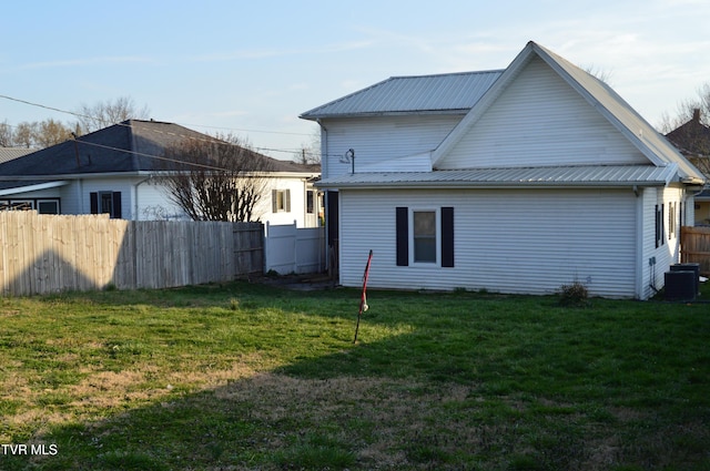 view of property exterior with metal roof, cooling unit, fence, and a yard