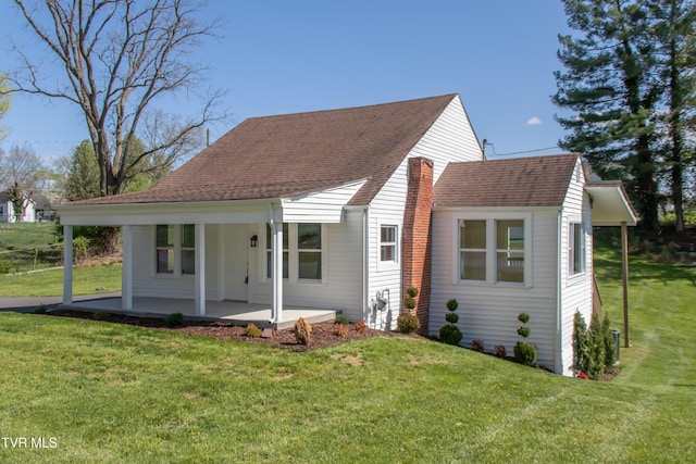 view of front of home featuring roof with shingles, covered porch, and a front yard