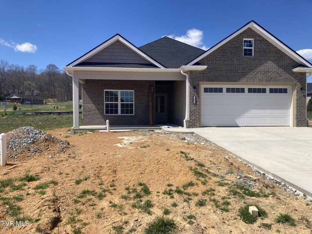 view of front of house featuring an attached garage, brick siding, concrete driveway, and a porch