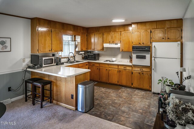 118 Starlite Dr, Greeneville, TN 37743 - kitchen with white appliances, under cabinet range hood, a sink, a peninsula, and brown cabinets