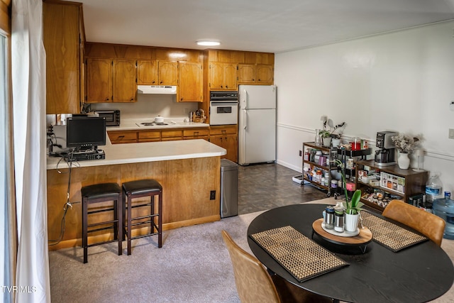 118 Starlite Dr, Greeneville, TN 37743 - kitchen featuring light countertops, a peninsula, white appliances, under cabinet range hood, and brown cabinetry
