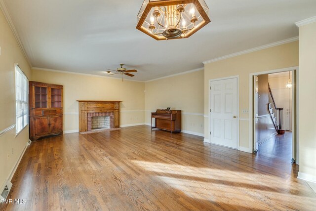 2017 Springfield Ave, Kingsport, TN 37664 - unfurnished living room with wood finished floors, a brick fireplace, baseboards, ceiling fan with notable chandelier, and ornamental molding