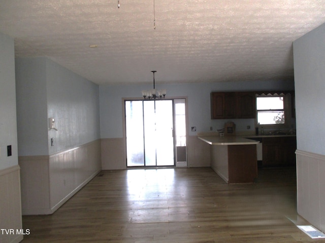 145 Rock City Rd, Kingsport, TN 37664 - kitchen with an inviting chandelier, a textured ceiling, a wainscoted wall, a peninsula, and wood finished floors