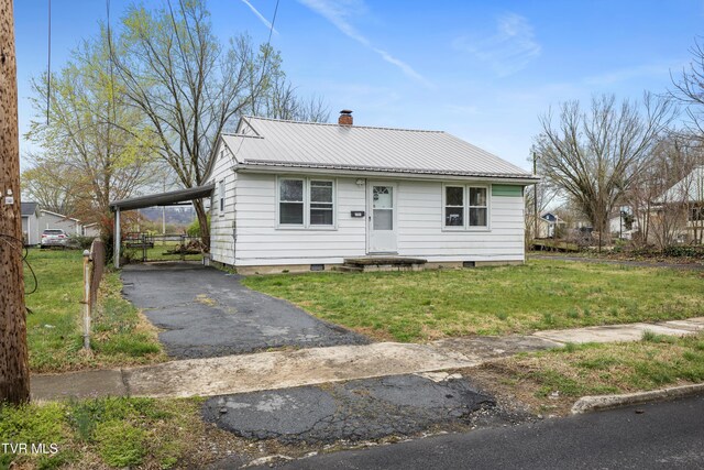 view of front facade with metal roof, a front yard, a chimney, and aphalt driveway