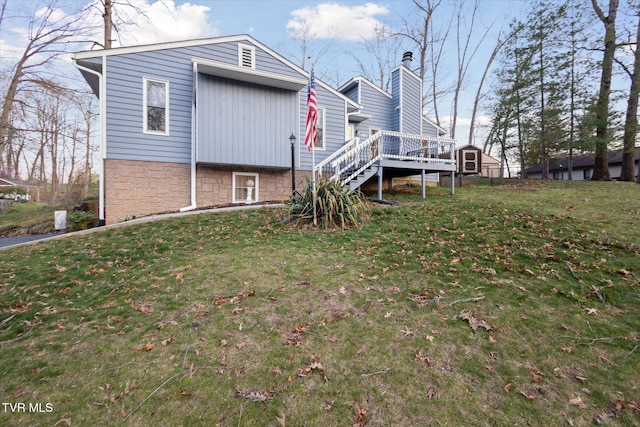 exterior space featuring a lawn, a chimney, a wooden deck, and stairway