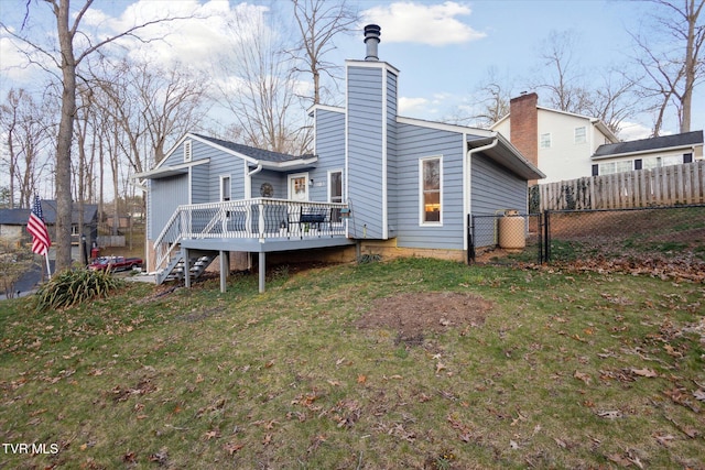 back of property with a gate, fence, a chimney, a deck, and a yard