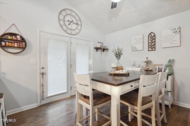 dining space featuring baseboards, lofted ceiling, wood finished floors, and a textured ceiling