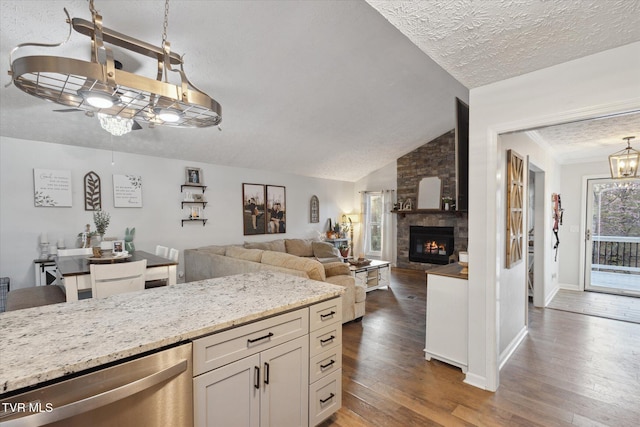 kitchen with decorative light fixtures, vaulted ceiling, dark wood-style flooring, stainless steel dishwasher, and a notable chandelier