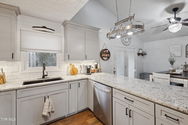 kitchen with visible vents, dishwasher, ceiling fan, a sink, and vaulted ceiling