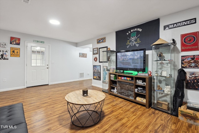 living room featuring baseboards, visible vents, and wood finished floors