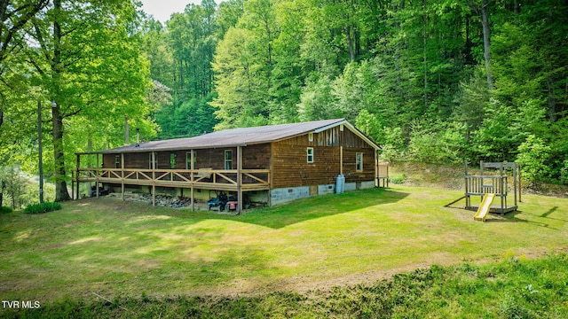 rear view of house featuring a lawn and a wooded view