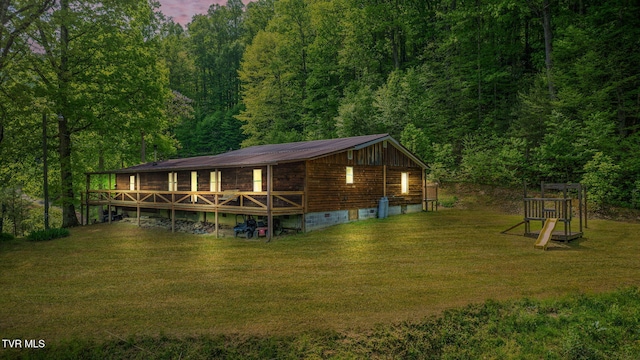 exterior space featuring a forest view, crawl space, metal roof, a lawn, and a deck