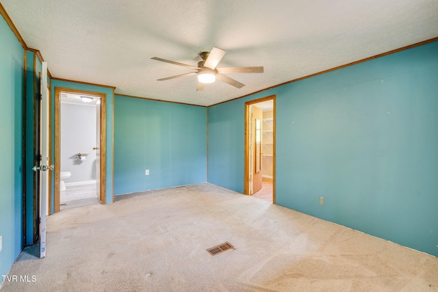 unfurnished bedroom with ceiling fan, a textured ceiling, visible vents, ensuite bathroom, and carpet flooring