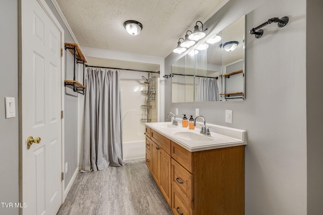 bathroom featuring a textured ceiling, a sink, shower / tub combo, and wood finished floors