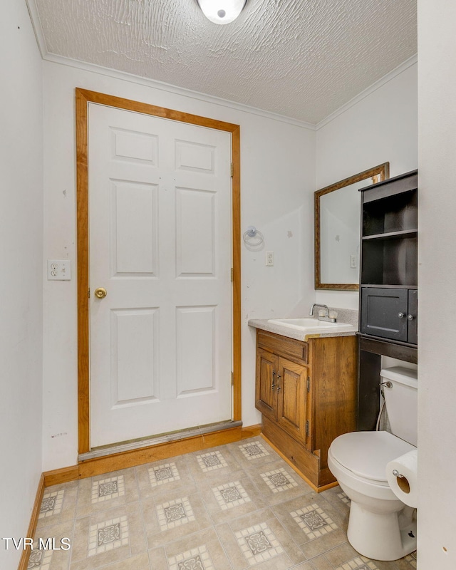 bathroom featuring vanity, ornamental molding, baseboards, and toilet