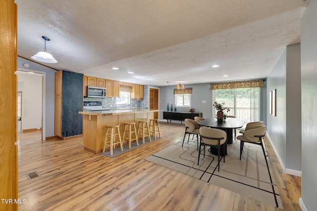 dining area featuring light wood-style floors, a textured ceiling, recessed lighting, baseboards, and visible vents