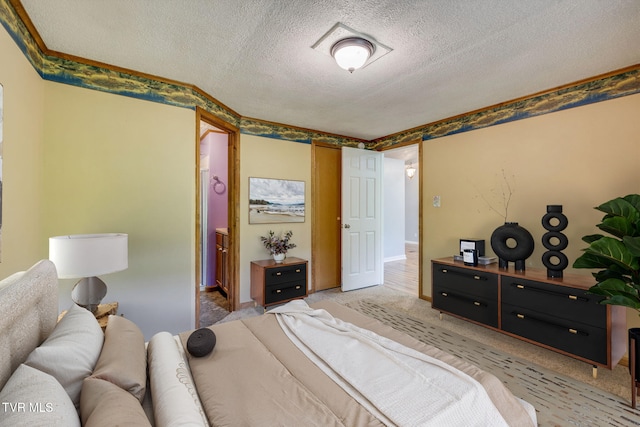 bedroom with connected bathroom, a textured ceiling, and light colored carpet
