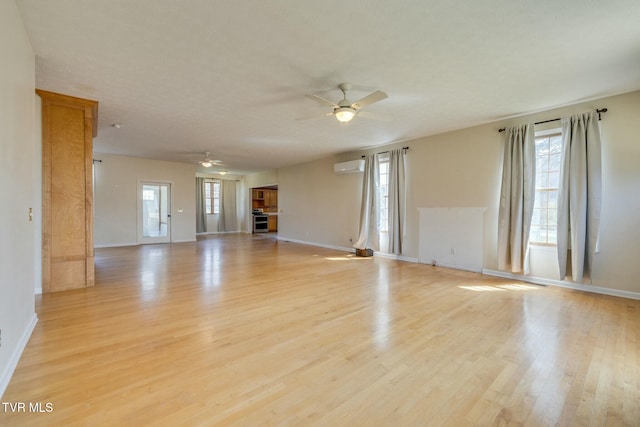 unfurnished living room featuring light wood-style flooring, a wall mounted AC, baseboards, and ceiling fan