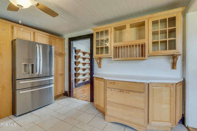 kitchen with light tile patterned floors, stainless steel fridge with ice dispenser, a ceiling fan, light brown cabinets, and glass insert cabinets