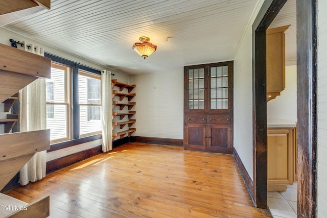 unfurnished dining area featuring baseboards and light wood-style flooring