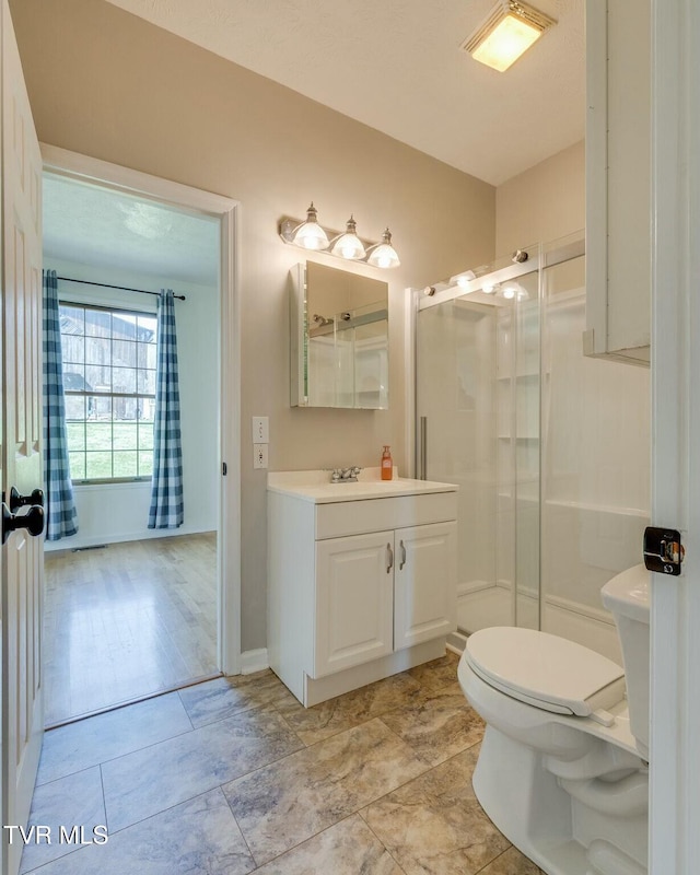 full bathroom with baseboards, toilet, a stall shower, and vanity