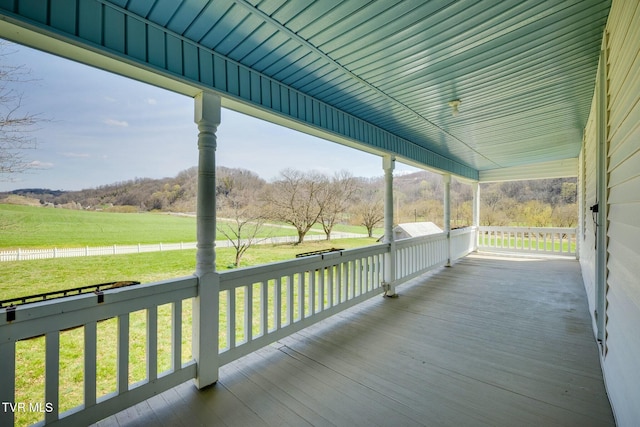 wooden terrace with a lawn, covered porch, and a rural view