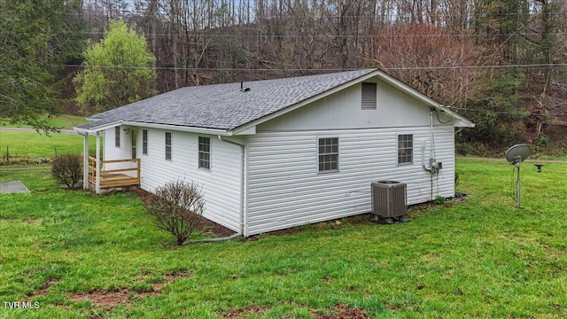 view of side of home with a lawn, a shingled roof, and central air condition unit