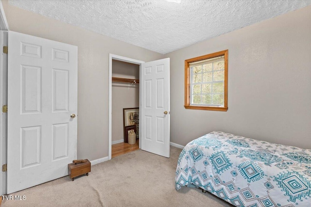 carpeted bedroom featuring baseboards, a closet, and a textured ceiling