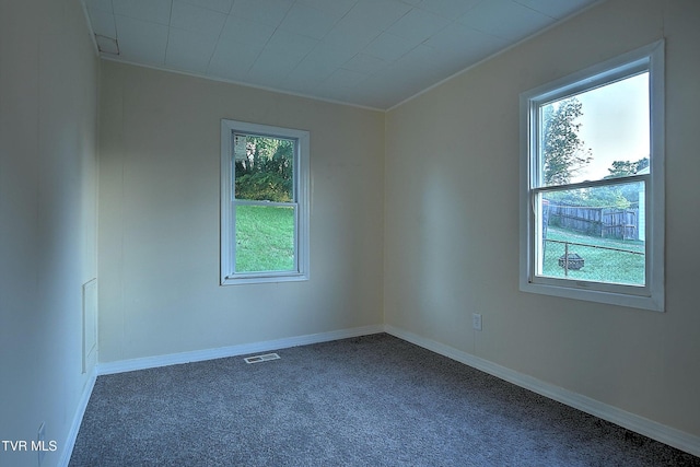 unfurnished room with baseboards, visible vents, and dark colored carpet