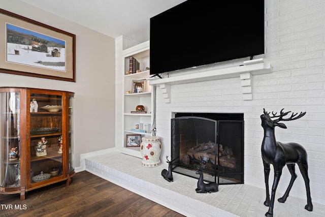 interior details with a brick fireplace, baseboards, wood finished floors, and built in shelves