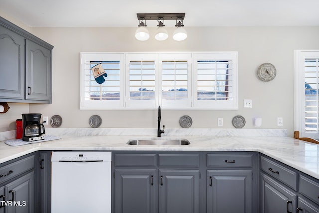 kitchen featuring gray cabinetry, dishwasher, light countertops, and a sink