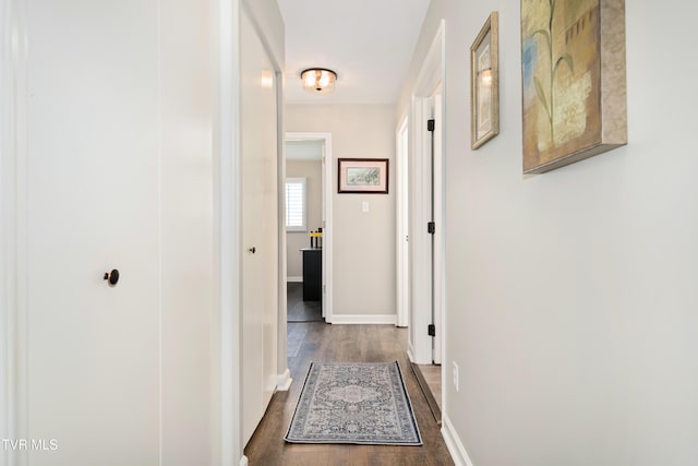 corridor featuring dark wood-type flooring and baseboards