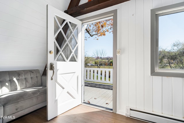 doorway featuring wood walls, baseboard heating, and wood finished floors
