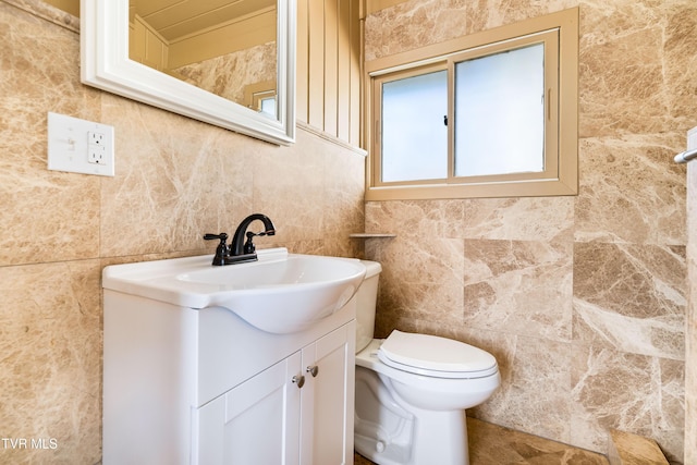 bathroom with vanity, tile walls, and toilet