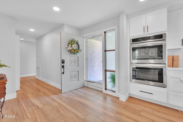 kitchen featuring white cabinets, recessed lighting, double oven, and light wood-style flooring