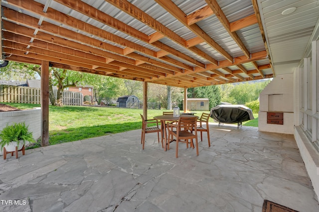 view of patio featuring an outbuilding, grilling area, outdoor dining space, and a shed