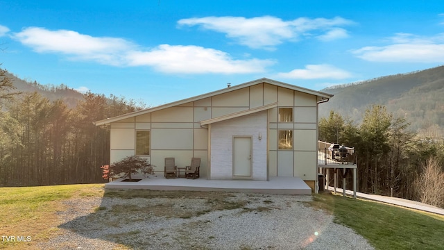 view of front facade featuring a front yard, a mountain view, and a patio