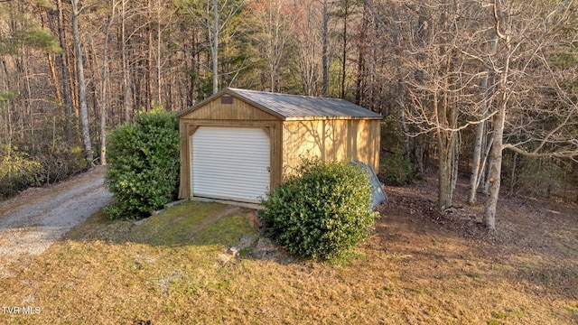 view of outbuilding featuring driveway, an outbuilding, and a forest view