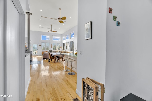 corridor with light wood finished floors, decorative columns, and recessed lighting