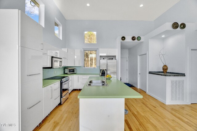 kitchen featuring white cabinets, visible vents, appliances with stainless steel finishes, a sink, and an island with sink