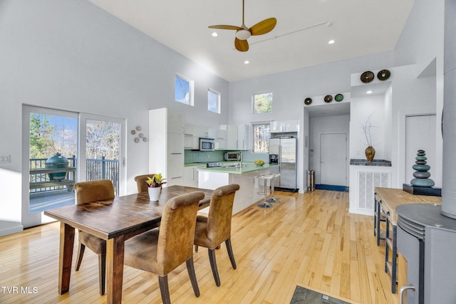dining space featuring a wealth of natural light, light wood-style floors, a towering ceiling, and ceiling fan