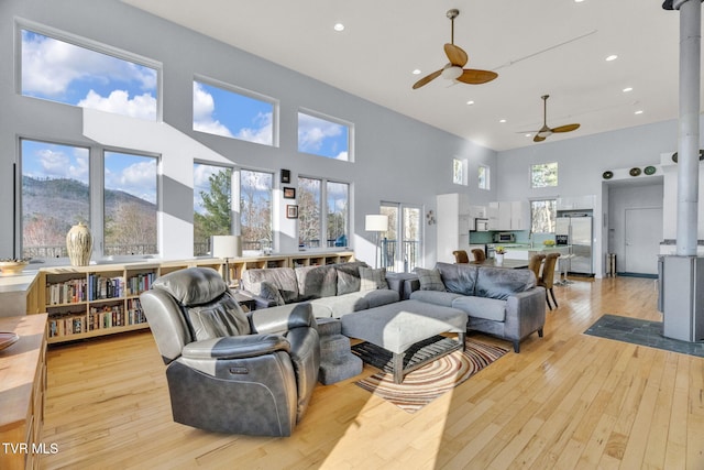 living area featuring a wealth of natural light, light wood-style floors, and a ceiling fan