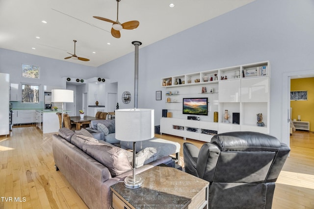 living area with a high ceiling, ceiling fan, light wood-style flooring, and recessed lighting