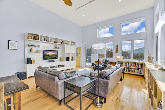 living room with light wood-style flooring and a towering ceiling